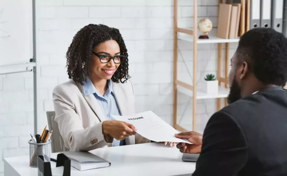 A woman giving her resume to the recruitment director in hopes to secure a position